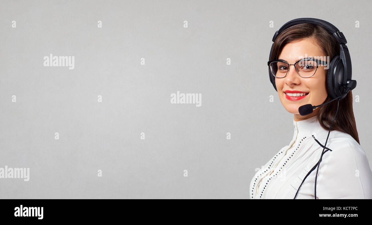 Woman call center operator in headset on gray background. Stock Photo