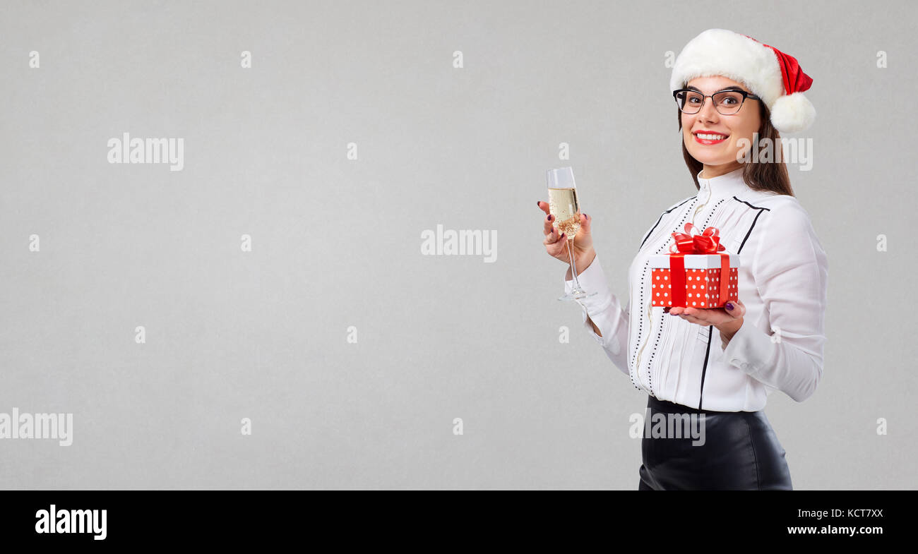 A girl in a santa hat with a glass of champagne and a gift in he Stock Photo