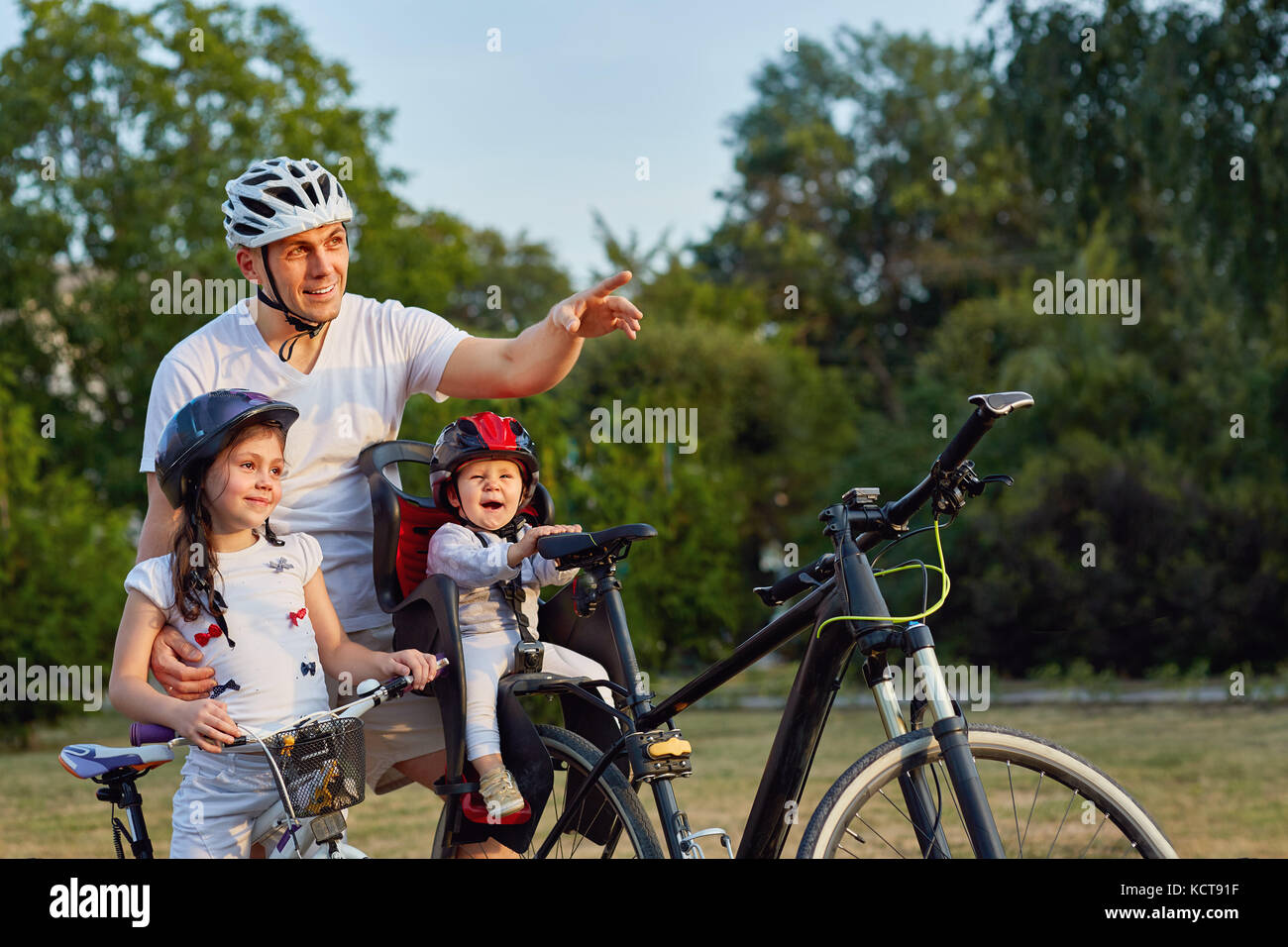Family in park, riding bicycles, looking at camera Stock Photo