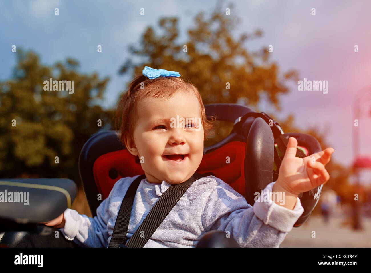 Closeup cute happy little baby on bike seat cycling in city park Stock