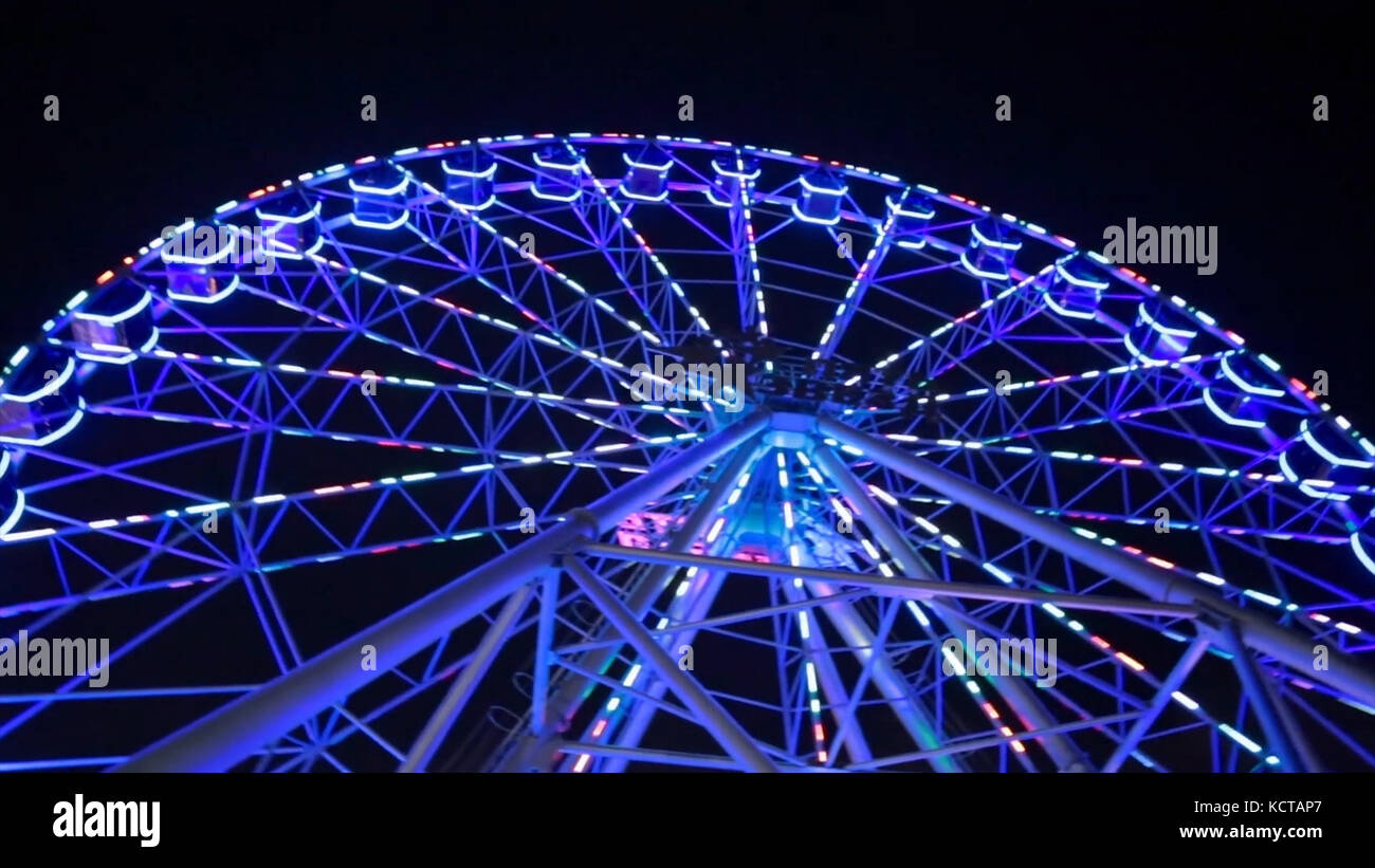 Ferris wheel in blue neon light on dark background, Part of Ferris wheel  with blue illumination against a black sky background at night. Ferris  wheel by night. Ferris wheel with multi-colored illumination