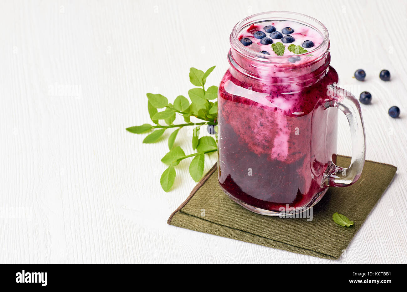 Jar of blueberry smoothie with berries and green leaves Stock Photo