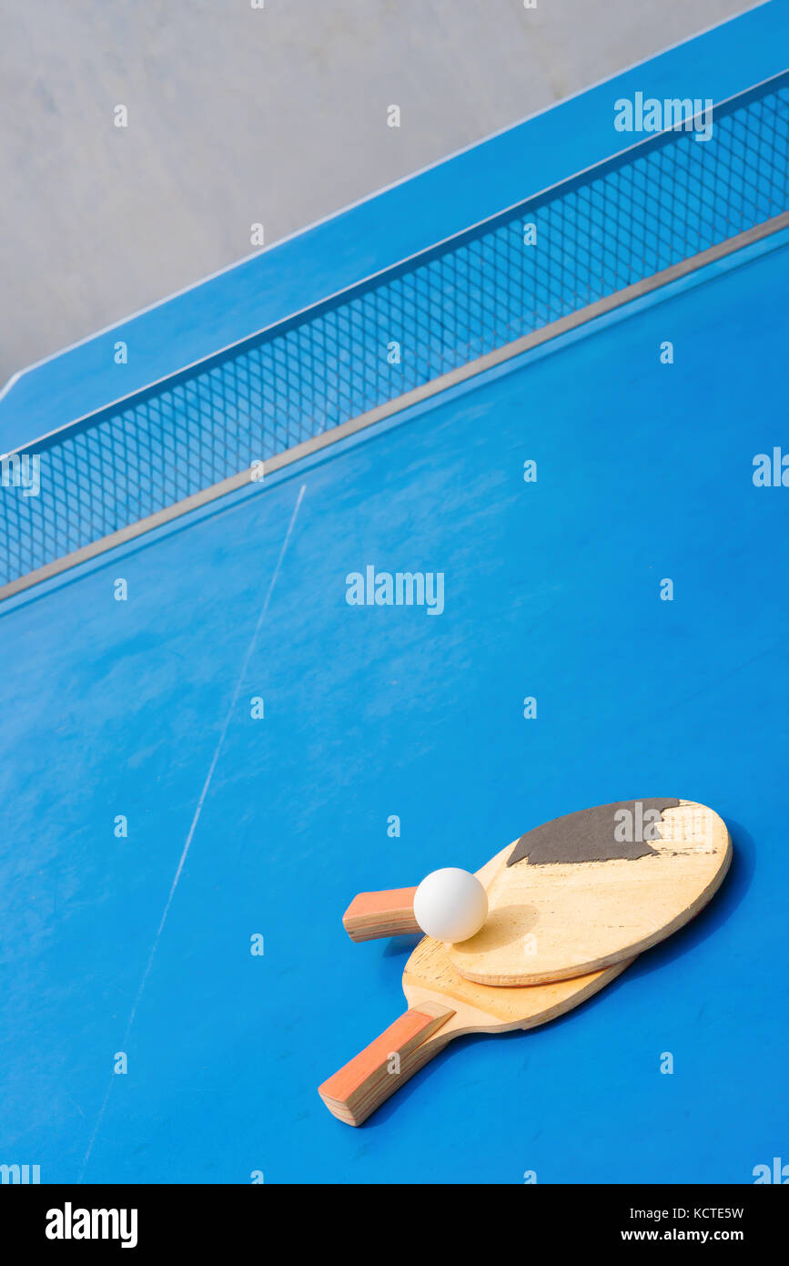 old pingpong rackets and ball and net on a blue pingpong table Stock Photo