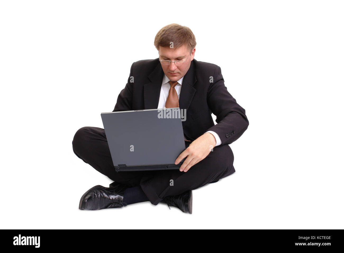 Young businessman in black suit sitting cross-legged working with ...