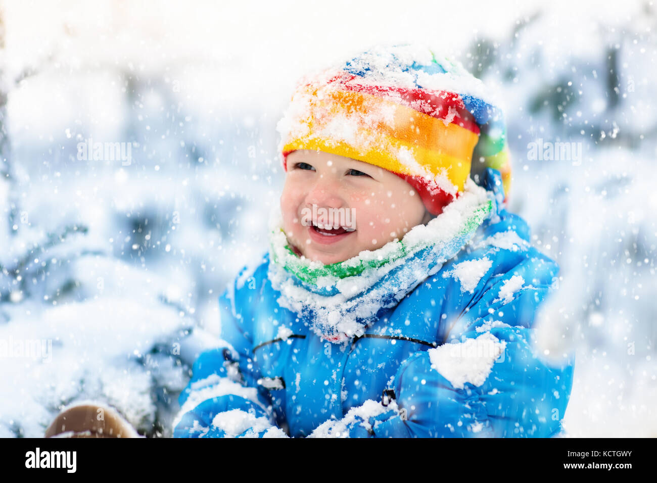 Baby playing with snow in winter. Little toddler boy in blue jacket and ...