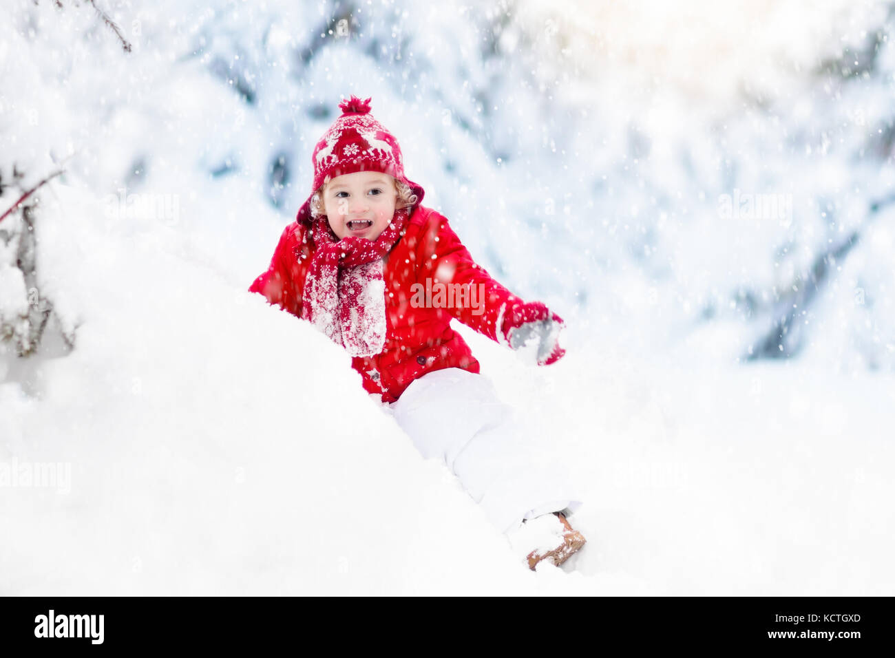 Child playing with snow in winter. Little boy in colorful jacket and ...