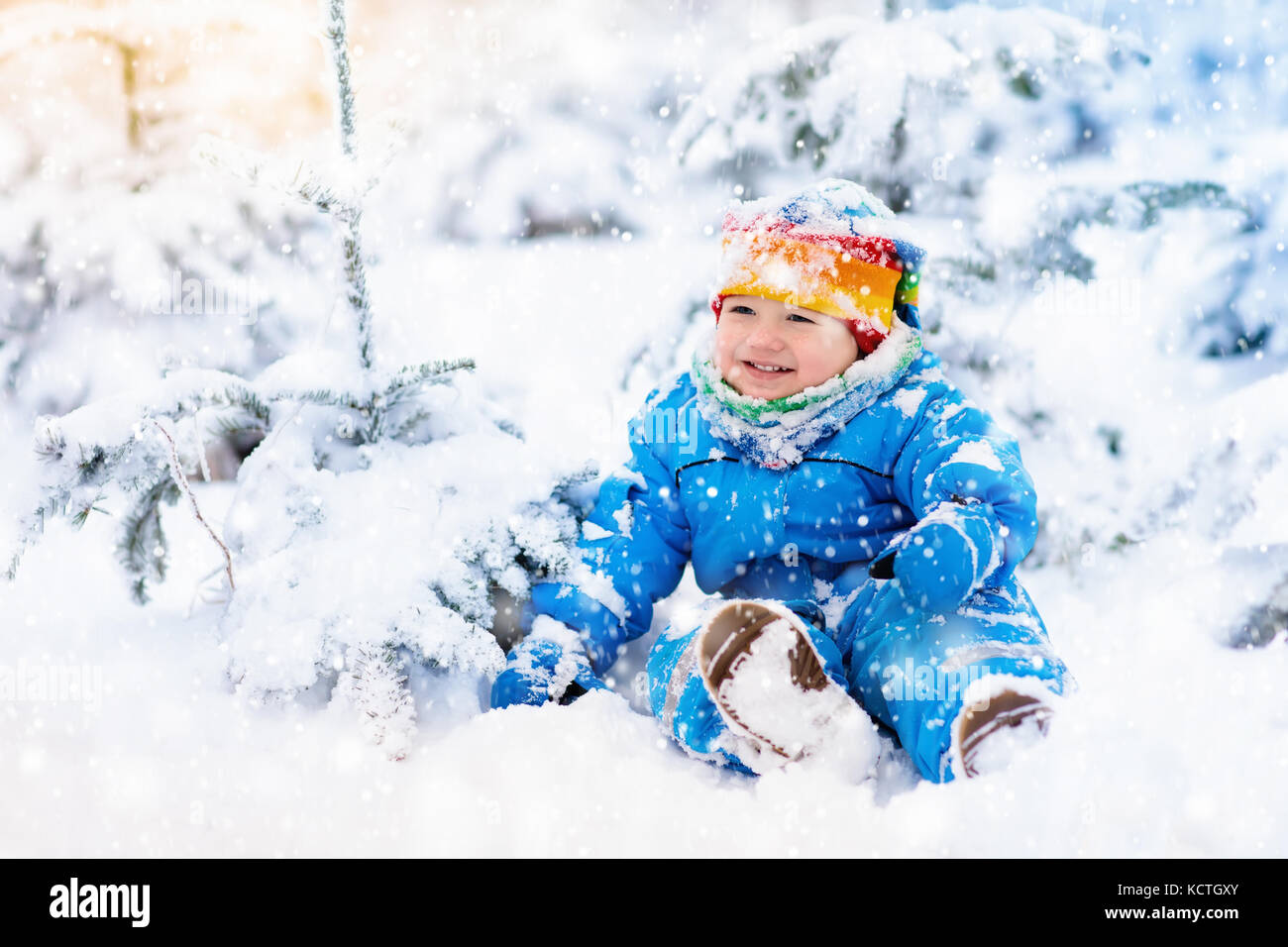 Baby playing with snow in winter. Little toddler boy in blue jacket and ...