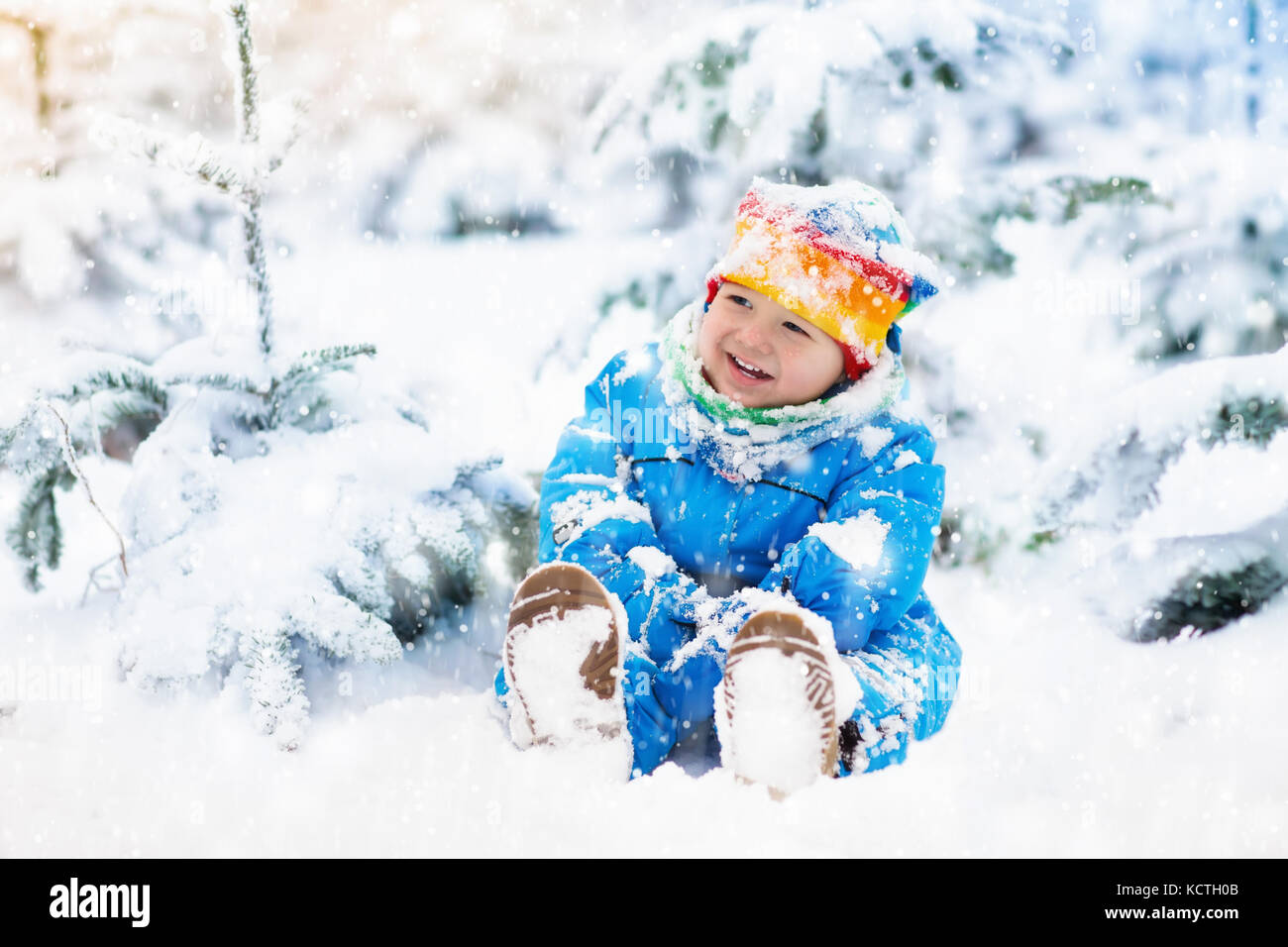 Baby playing with snow in winter. Little toddler boy in blue jacket and ...