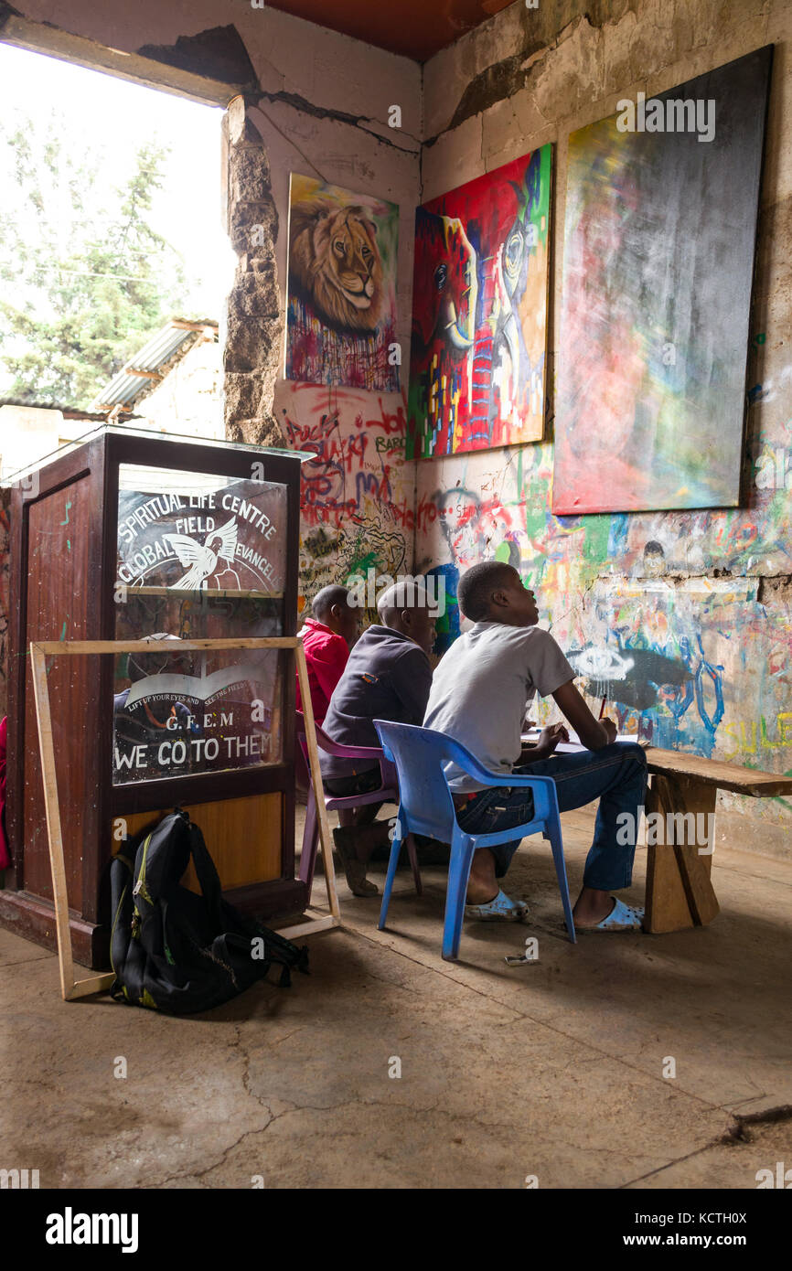 Young African children practice drawing and painting with artwork on walls of derelict building, Kibera slum, Nairobi, Kenya Stock Photo