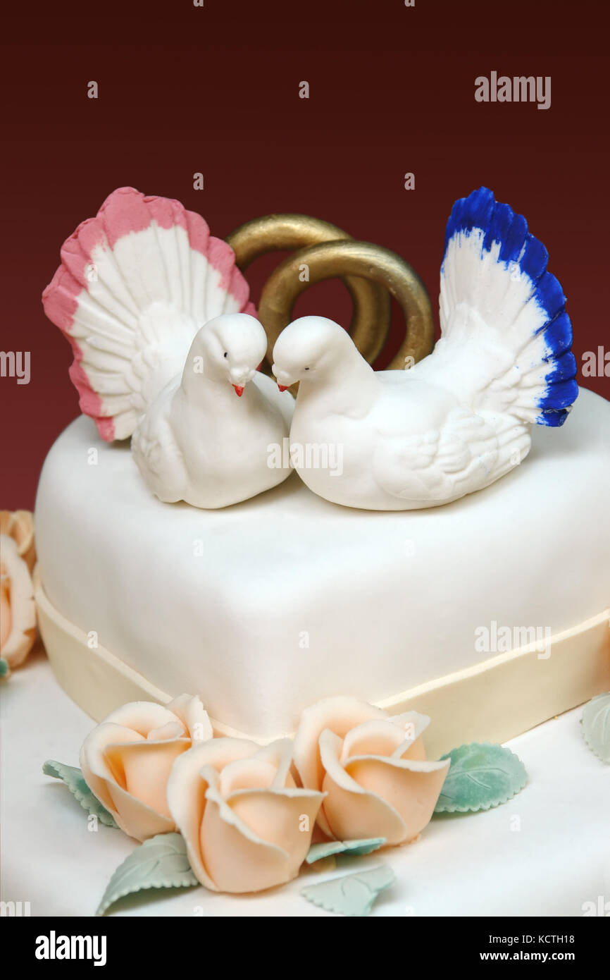 Closeup of white iced wedding cake with two white doves and wedding