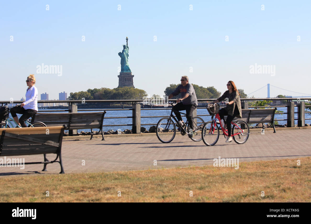 Statue of Liberty seen from Liberty State Park with people walking and