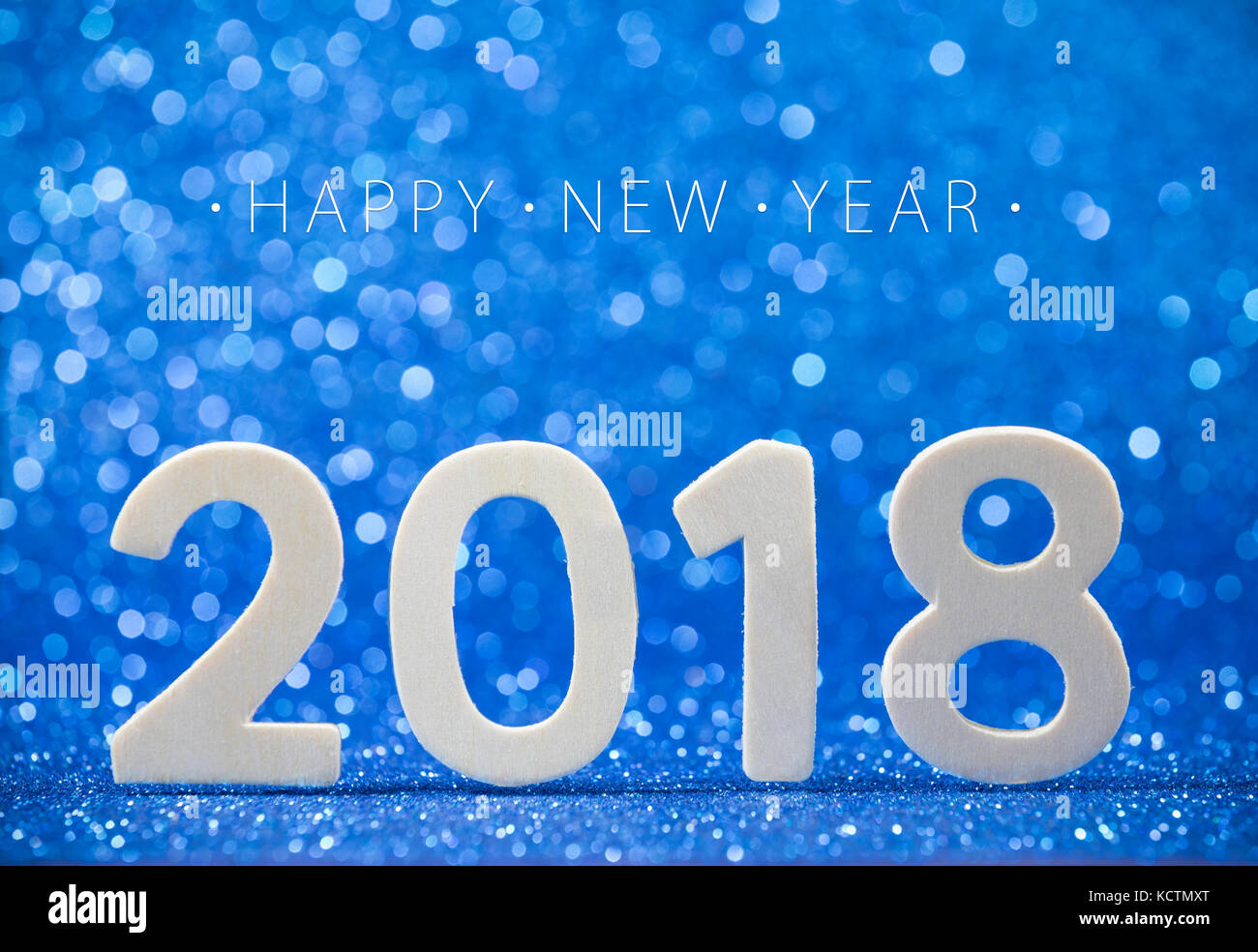 Happy New Year 2018 white wood number on blue paper with glitter lights. Stock Photo