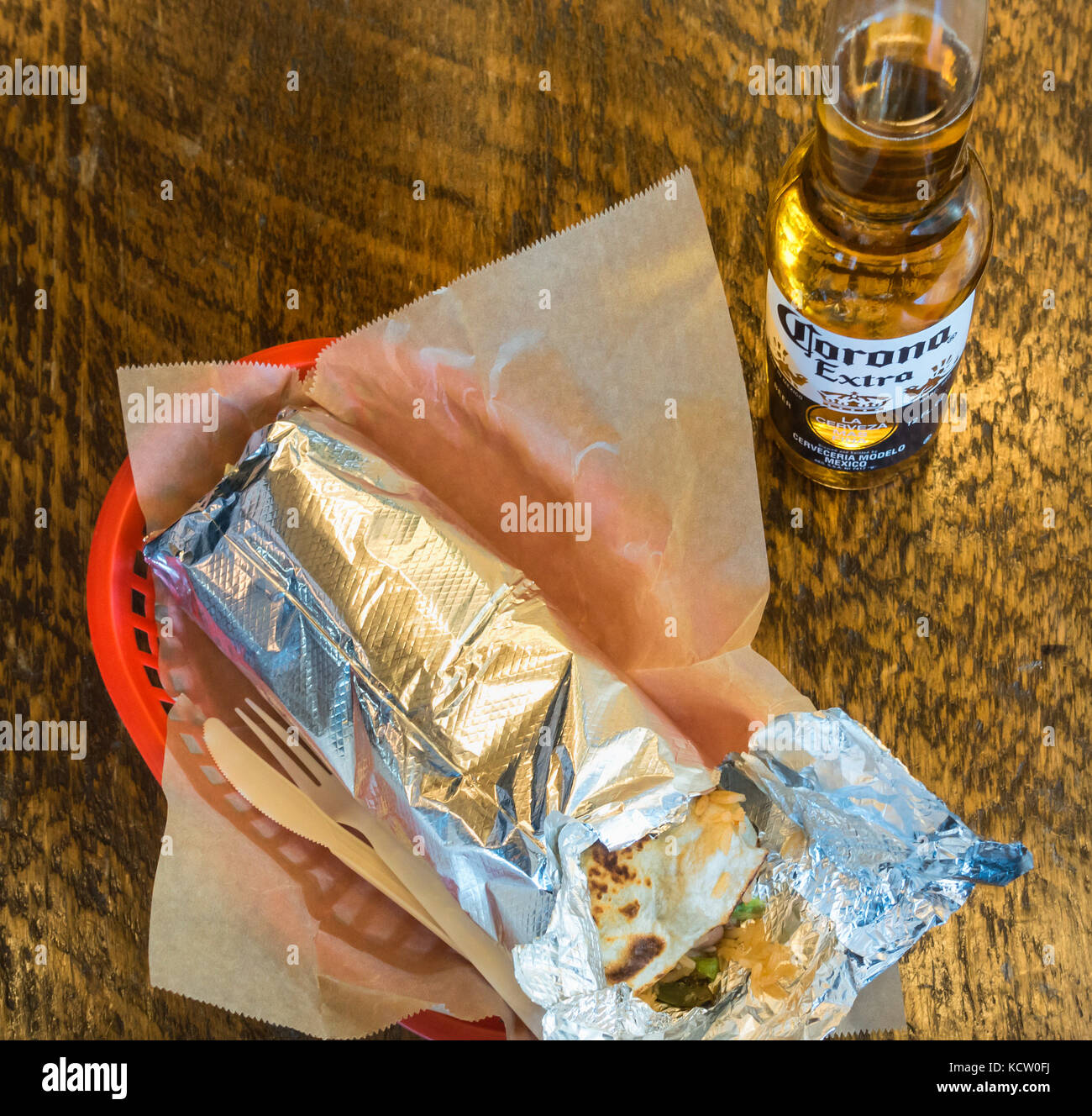 A large takeout quesadilla wrapped in tinfoil with a bottle of Corona Extra beer Stock Photo
