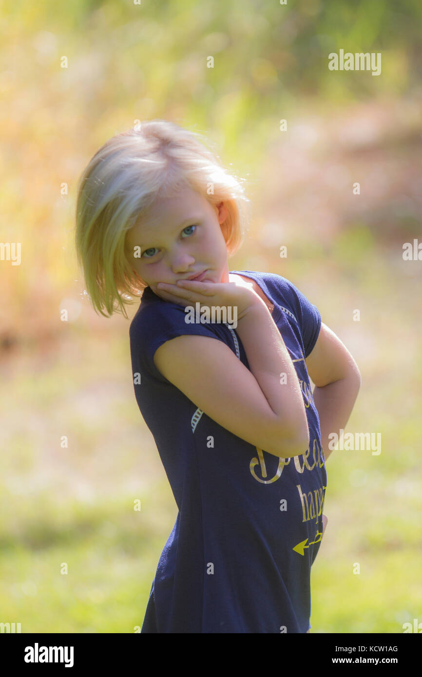 Pretty blonde young girl, posing and looking at camera, in back light sunshine. Cranbrook, BC, Canada Stock Photo