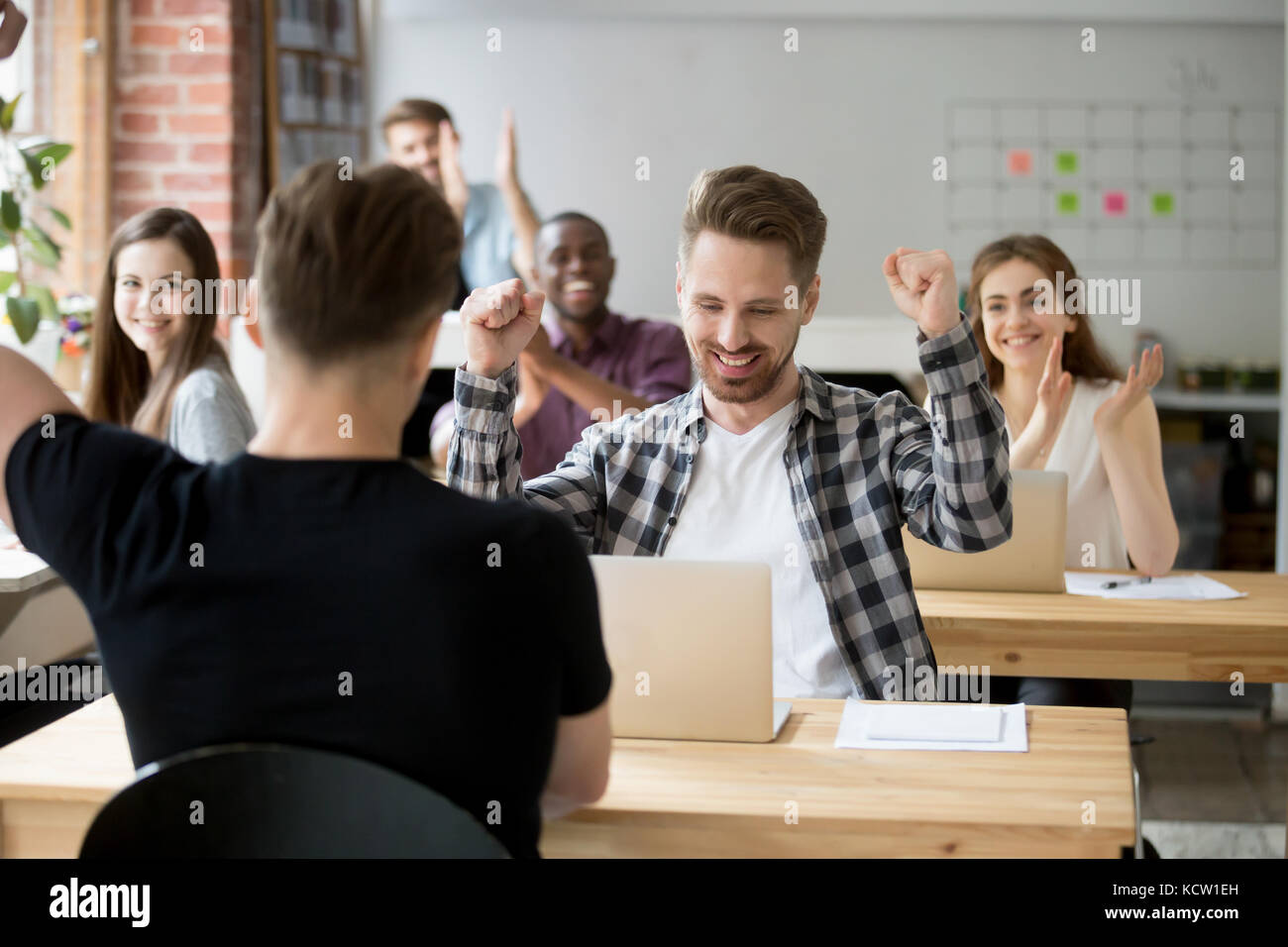 Young casually dressed male office worker throws hands in air