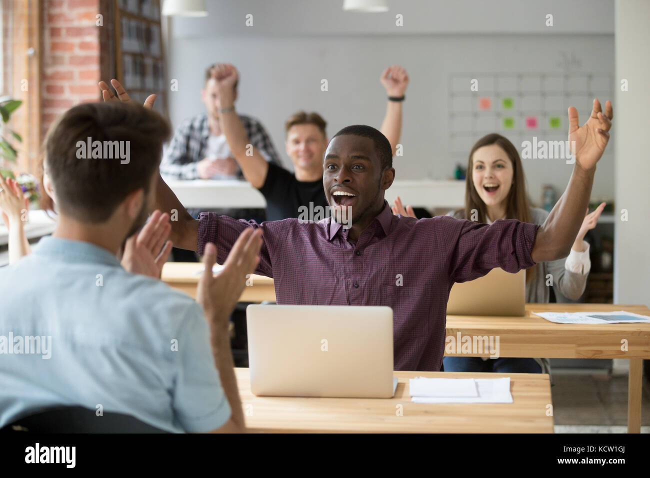 Young african american office worker throws hands in air celebrating