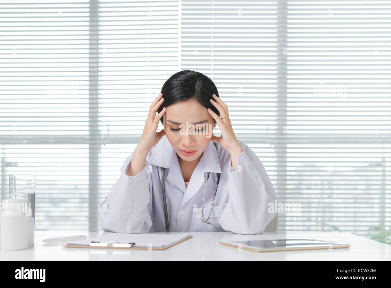 Frustration young female doctor sitting in her consulting room Stock Photo