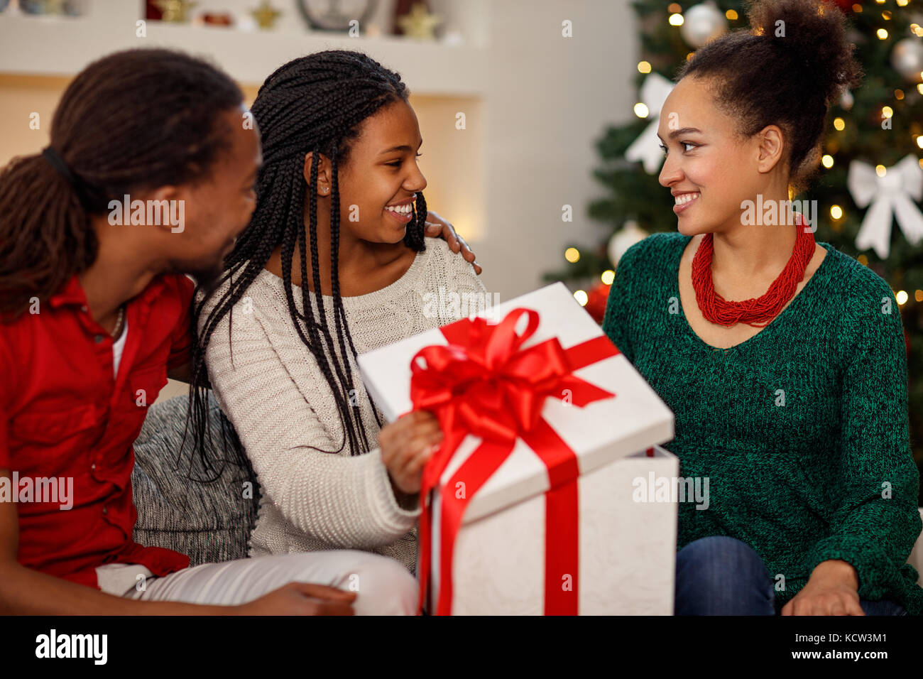 African smiling daughter receiving Christmas gift from parents Stock ...