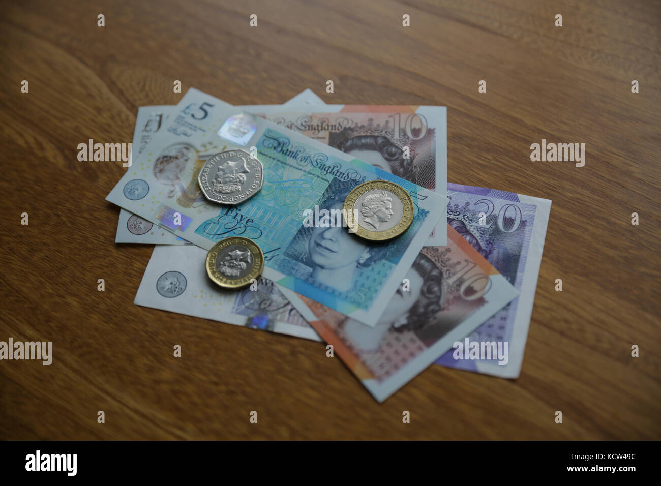 A selection of British currency on a wooden surface Stock Photo