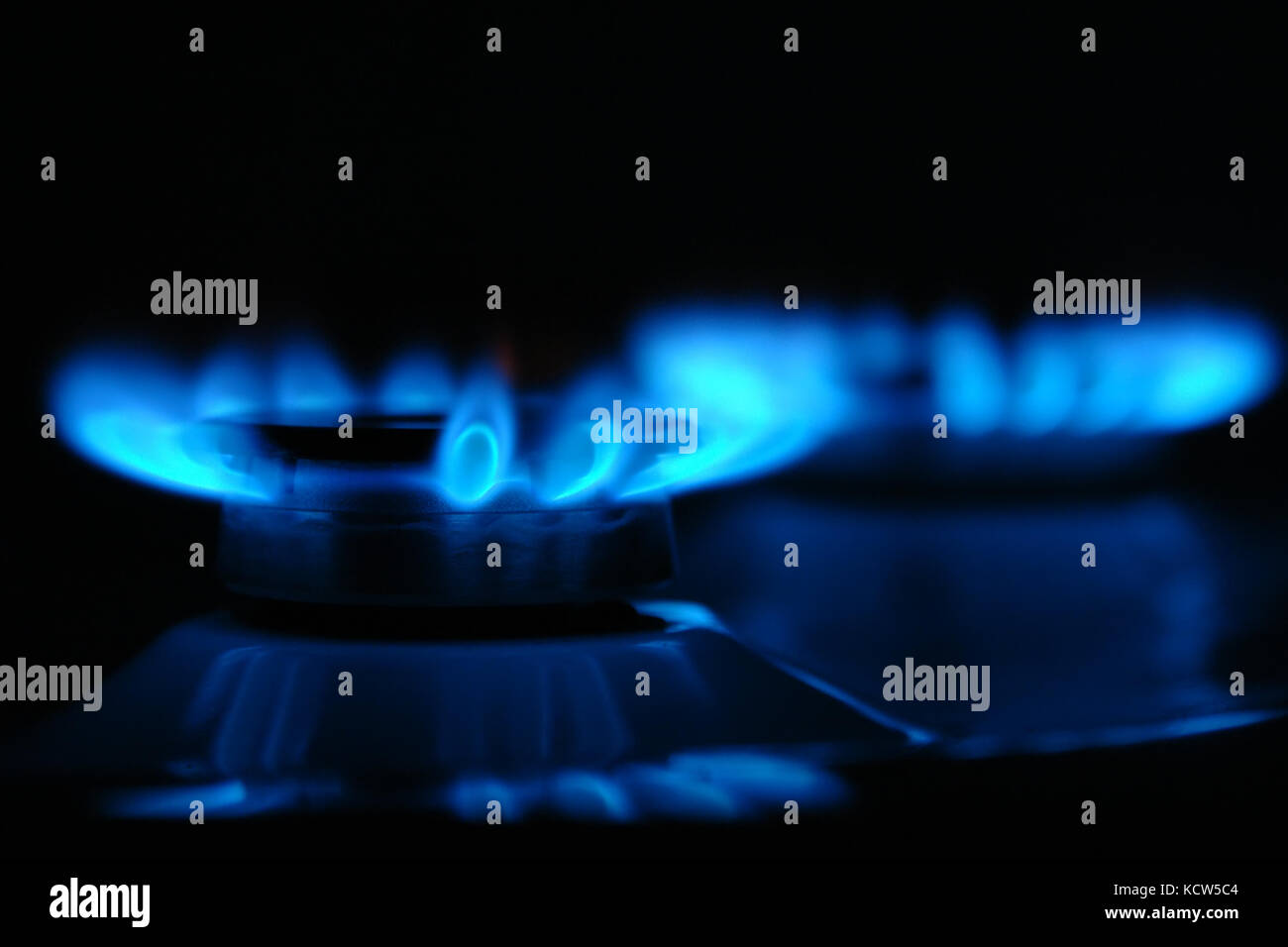 Closeup of two gas cooker burners lit in the darkness Stock Photo