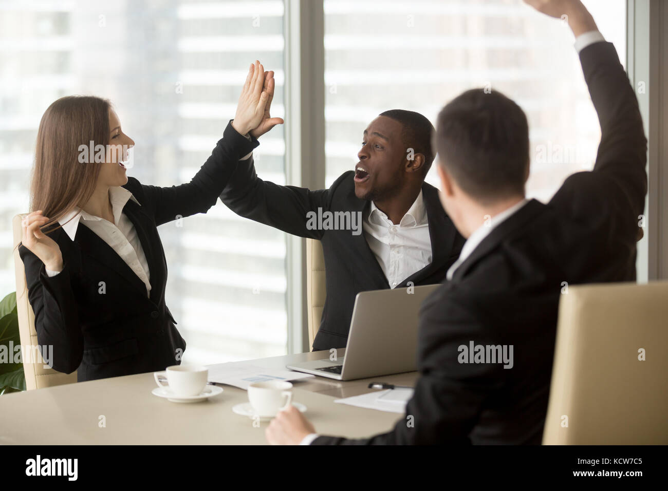 Excited office workers giving high five celebrating wages or sales increase, successful deal, promotion at work concept. Happy diverse ethnicity busin Stock Photo