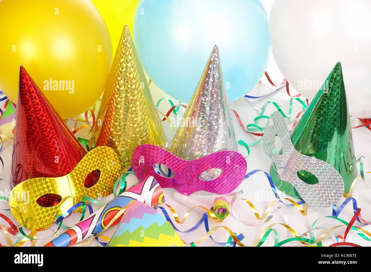 Four cone party hats, streamers, balloons and carnival masks Stock Photo