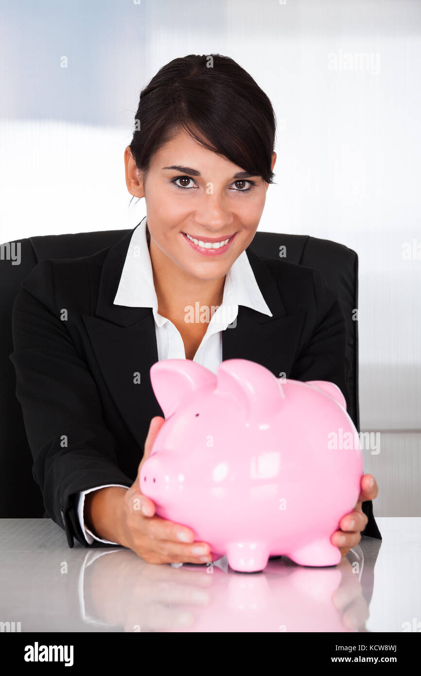 Young Happy Businesswoman Holding Pink Piggy Bank At Desk Stock Photo ...