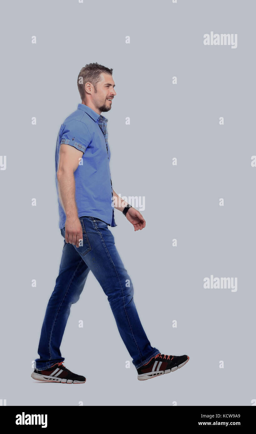 side view of a smiling young casual man walking , on white backg Stock Photo