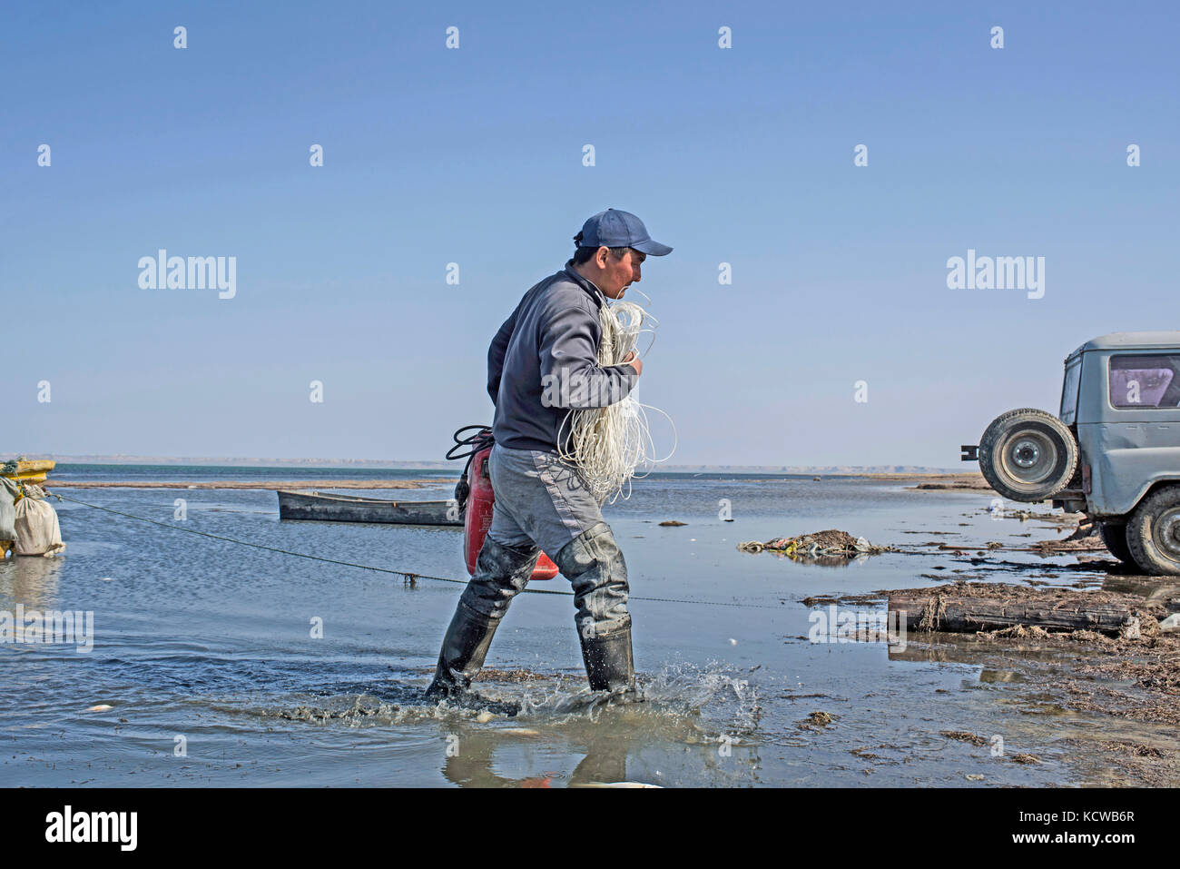 Nurzhan puts his equipment after a morning of fishing. Long thirteen kilometers, the dam has allowed the small sea to win back 50% of its surface. The Stock Photo