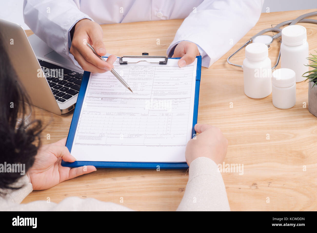 Patient and doctor taking notes on health insurance paperwork Stock Photo