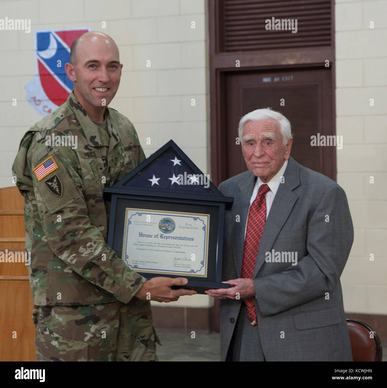 Mr. William Zimmerman receives a U.S. Flag flown over the S.C. state house from U.S. Army Lt. Col. Ryan Price, 228th Theater Tactical Signal Brigade deputy commander, in recognition of his service during a ceremony at the South Carolina Army National Guard Armory in Graniteville, S.C., Nov. 4, 2016. The South Carolina National Guard honored Zimmerman as its oldest living retiree at age 97. Zimmerman served for more than 34 years, which included service during World War II. (U.S. Army National Guard photo by Capt. Brian Hare) Stock Photo