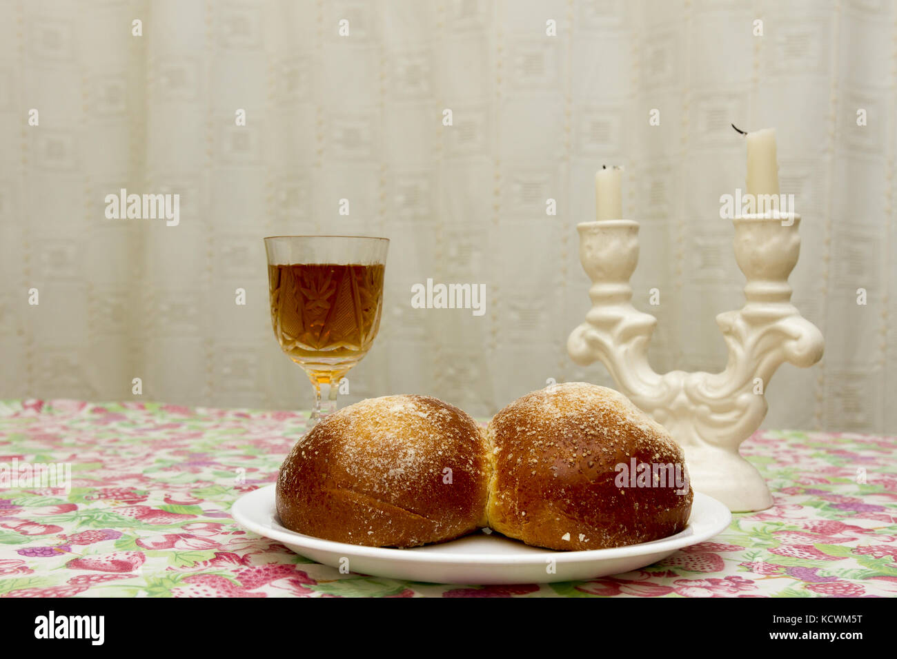 Shabbat candles in glass candlesticks with blurred covered challah