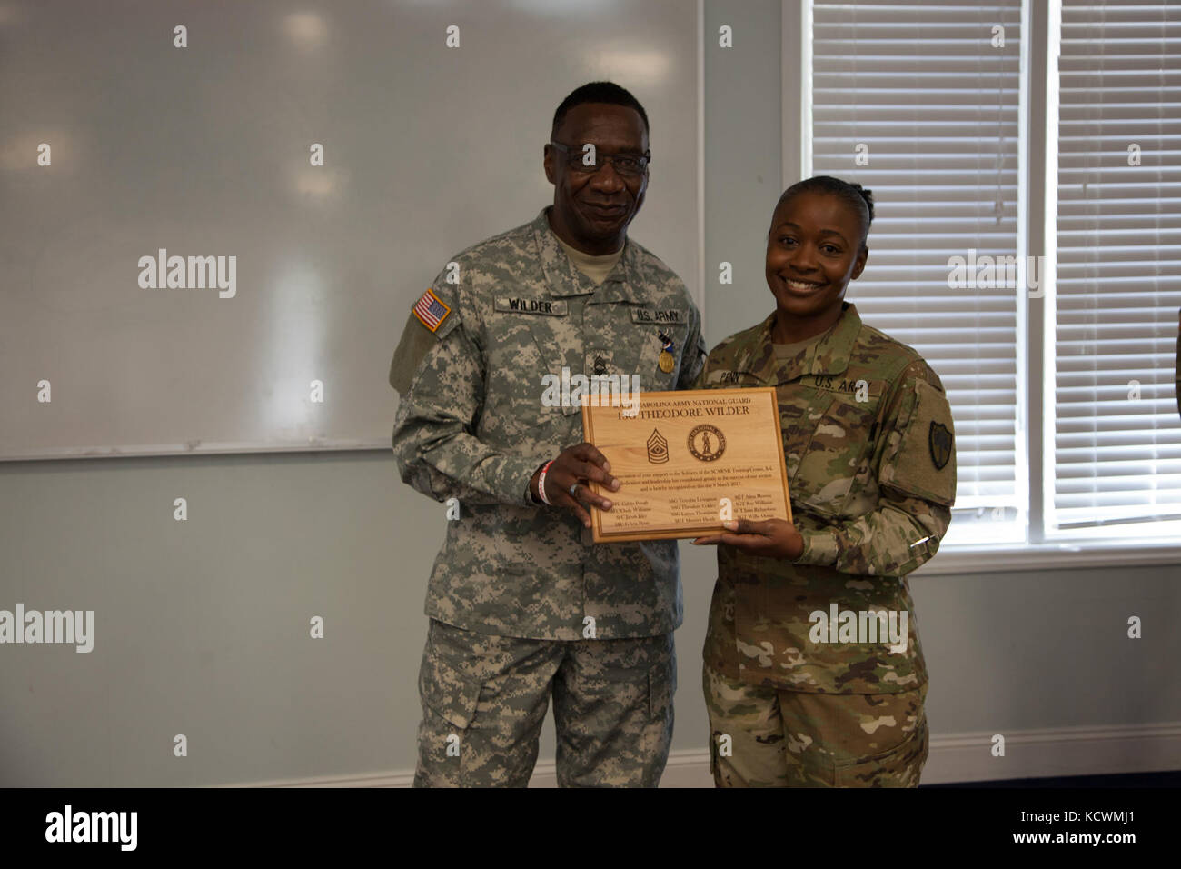 U.S. Army Sgt. 1st Class Felicia Penn presents Master Sgt. Theodore Wilder with a retirement award as the South Carolina National Guard recognizes Wilder’s 37 years of service during a retirement ceremony at McCrady Training Center in Eastover, South Carolina, March 9, 2017. (U.S. Army National Guard photo by Capt. Brian Hare) Stock Photo