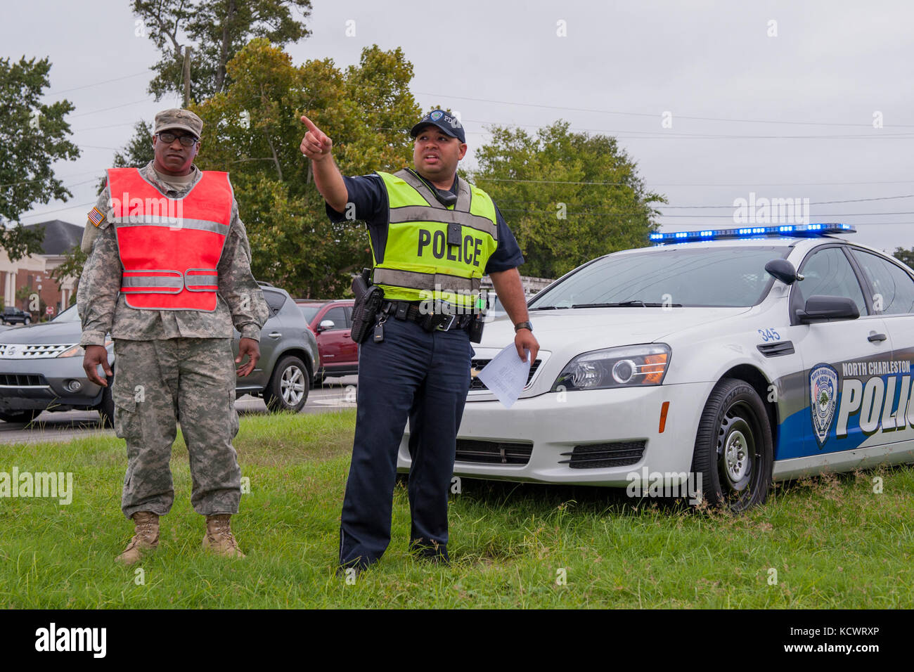 U.S. Army Pvt. 1st Class Bradley Burgess, C Company, 1st Battalion 118th Infantry Regiment, South Carolina Army National Guard, and City of North Charleston Patrolman 1st Class Giovanni Brown manage a traffic control point in North Charleston, South Carolina, Oct. 5, 2016.  Hurricane Matthew peaked as a Category 4 hurricane in the Caribbean and was projected to pass over the southeastern U.S., including the S.C. coast. Approximately 1,400 S.C. National Guard Soldiers and Airmen were activated Oct. 4, 2016, to support coastal evacuations after Governor Nikki Haley declared a State of Emergency. Stock Photo