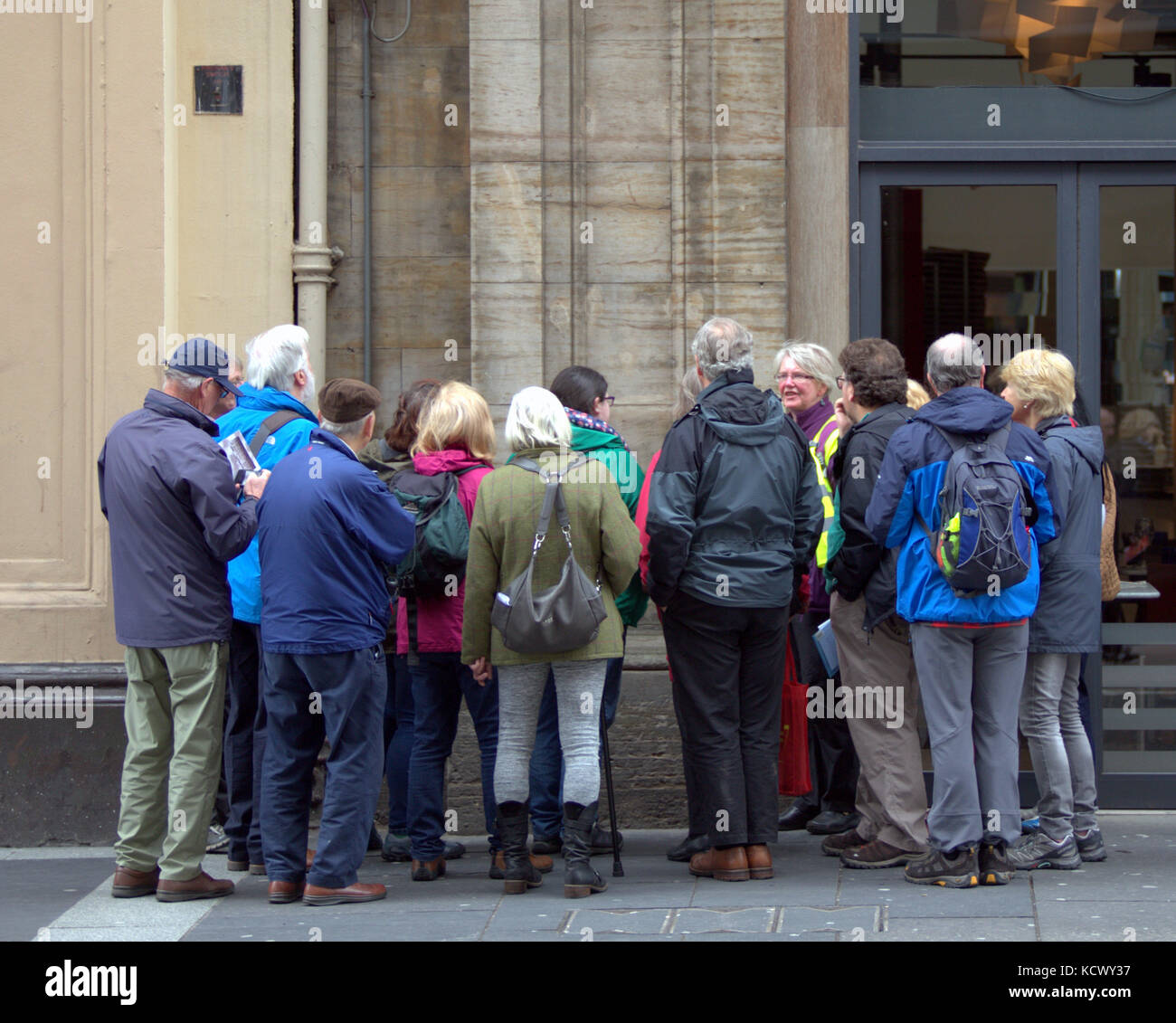 crowd of seniors  middle aged tourists and guide  on glasgow street viewed from behind Stock Photo