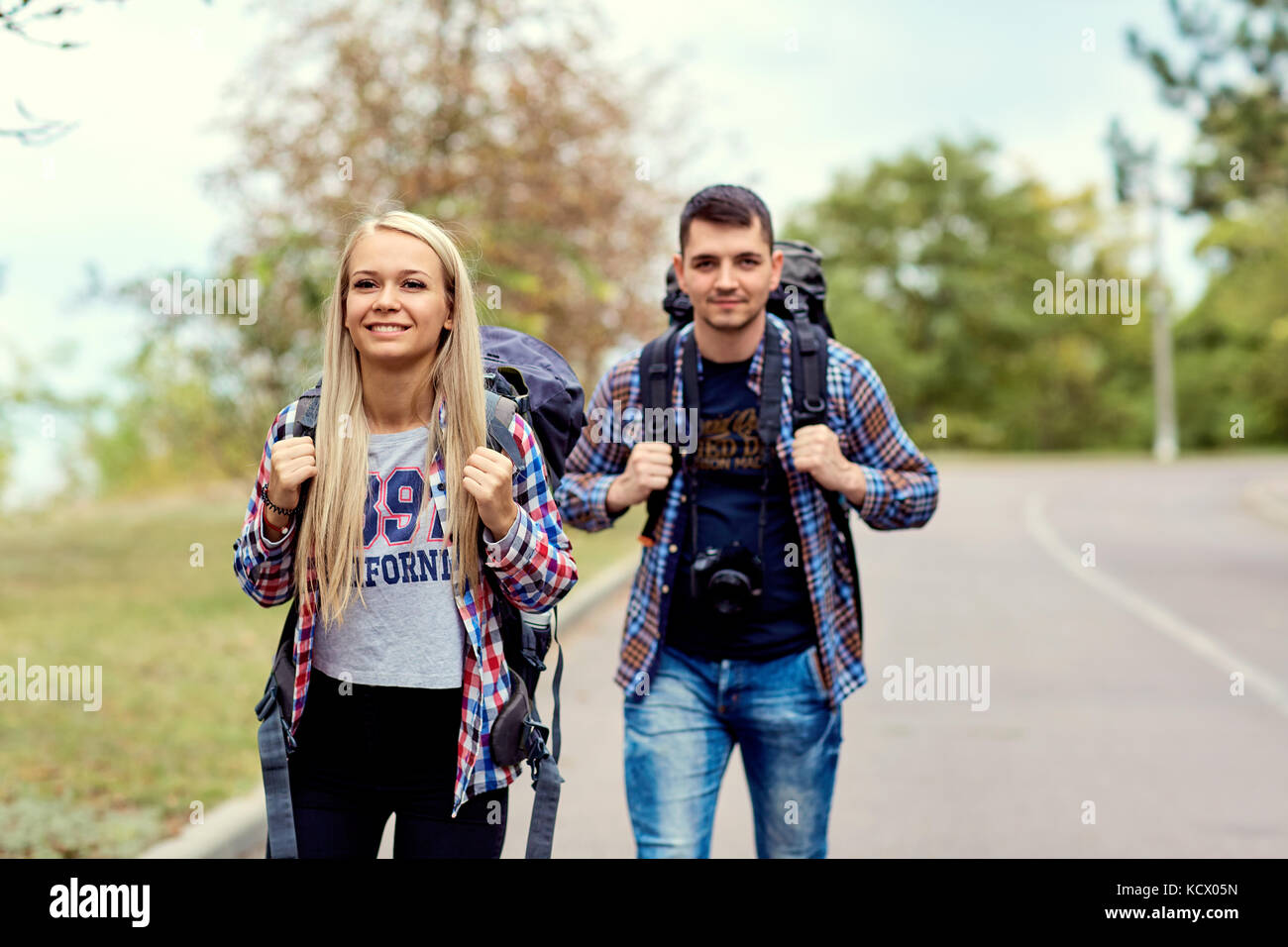 A young couple of tourists hikers in a hike on the road Stock Photo