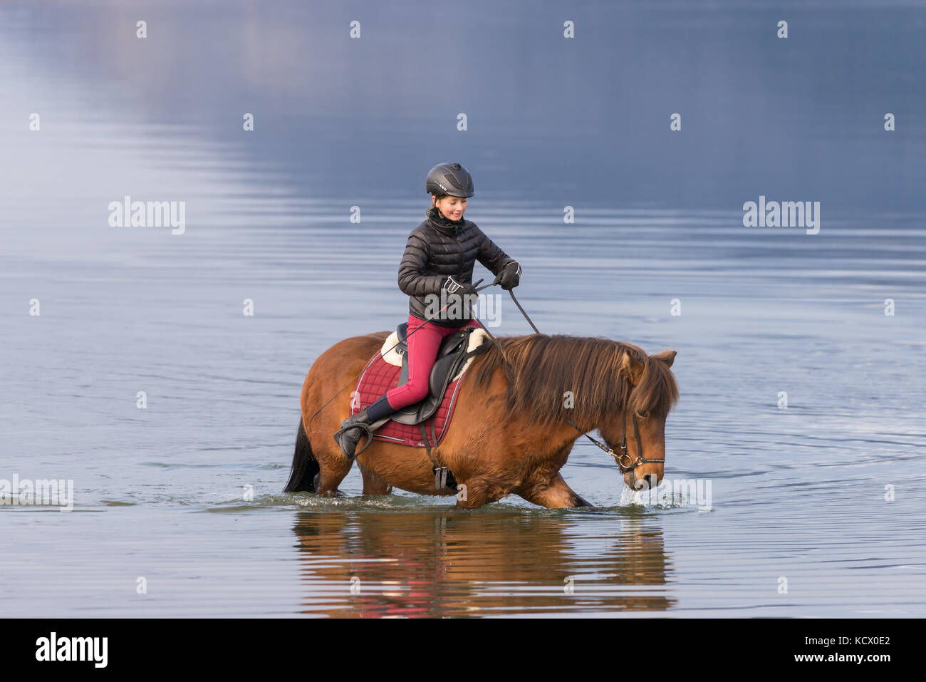 Young teen girl riding horse in ocean at a beach Stock Photo