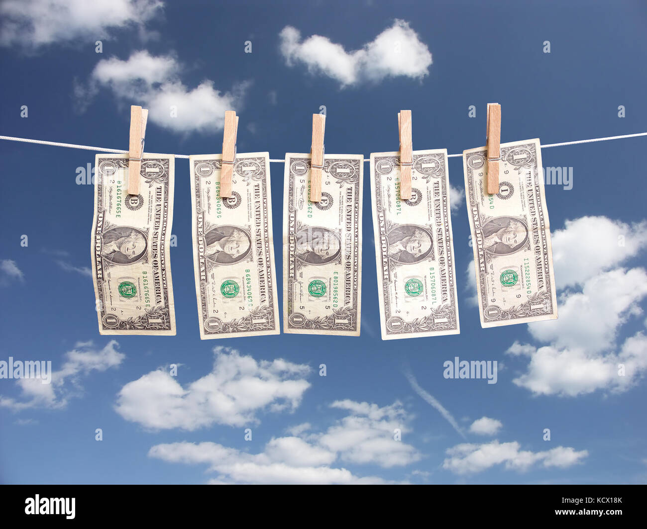 One dollar bills hanging on laundry line attached with wooden clips over blue sky Stock Photo