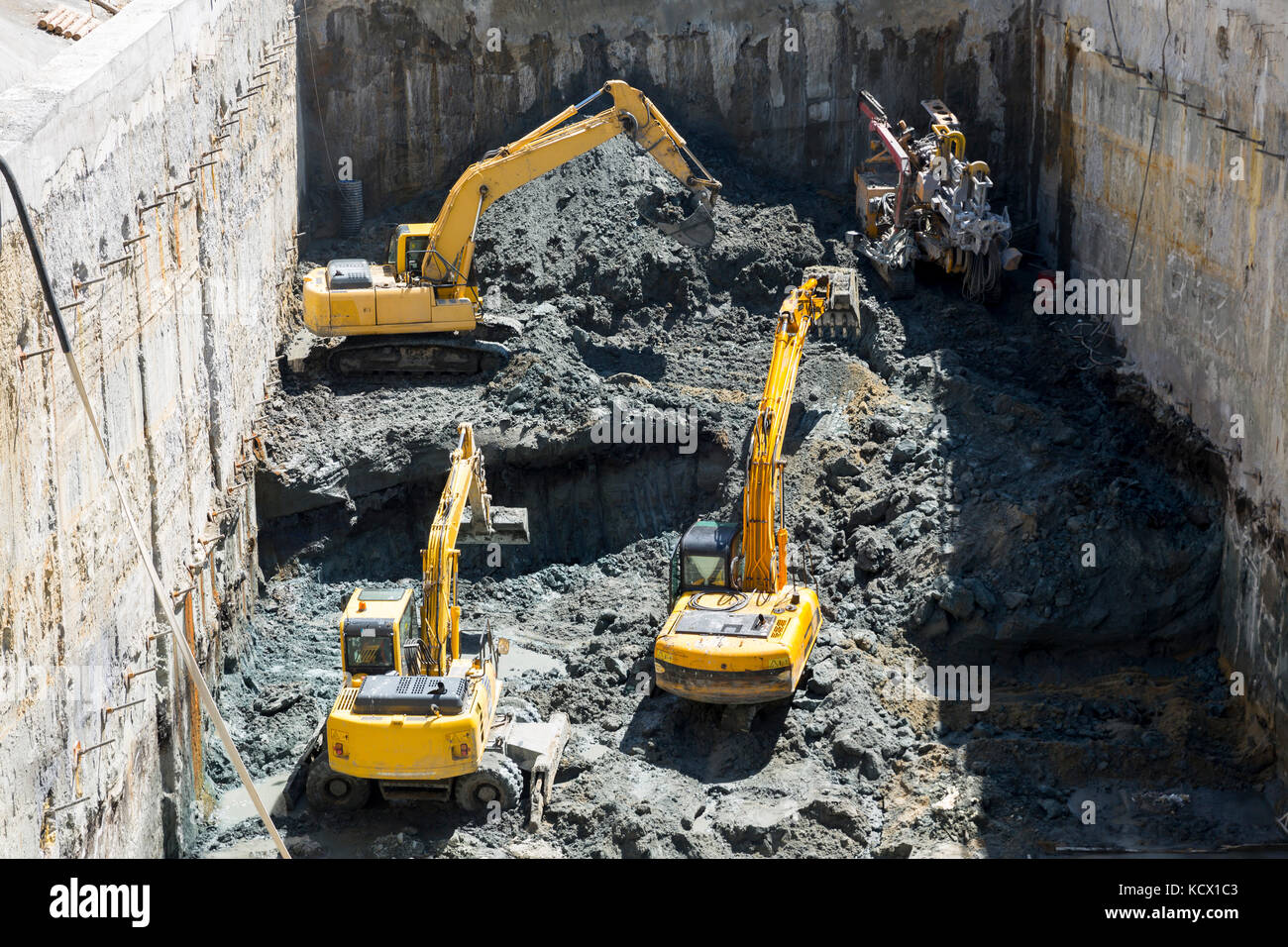 Excavators dig at a construction site of a street and a subway. Baggers transport dirt to a higher level to make room for the subway digging machine.  Stock Photo