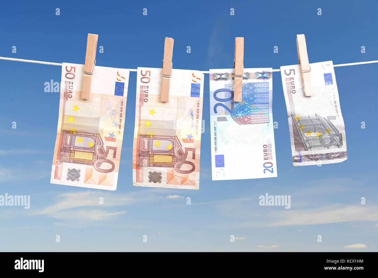 Fifty, twenty and five euro banknotes hanging on laundry line attached with wooden clips over blue sky Stock Photo