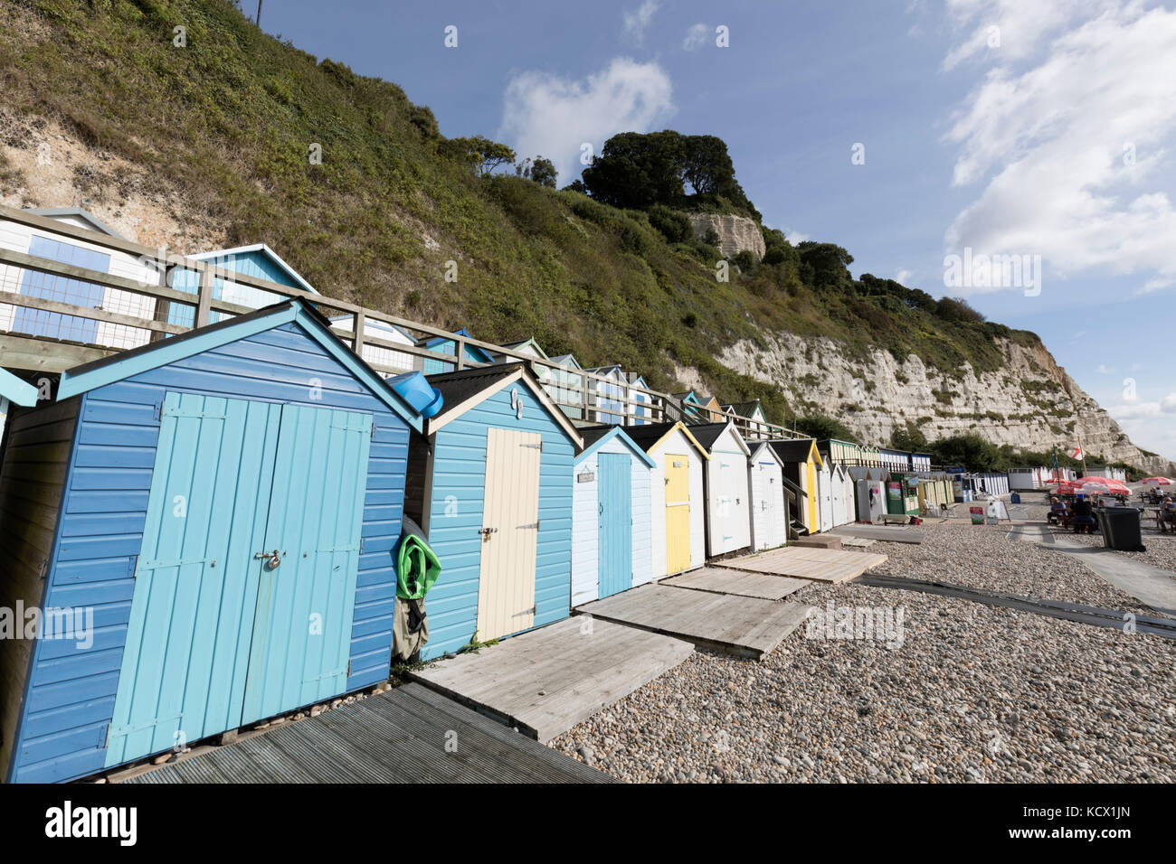 Beach huts on shingle beach below white cliff, Beer, Devon, England