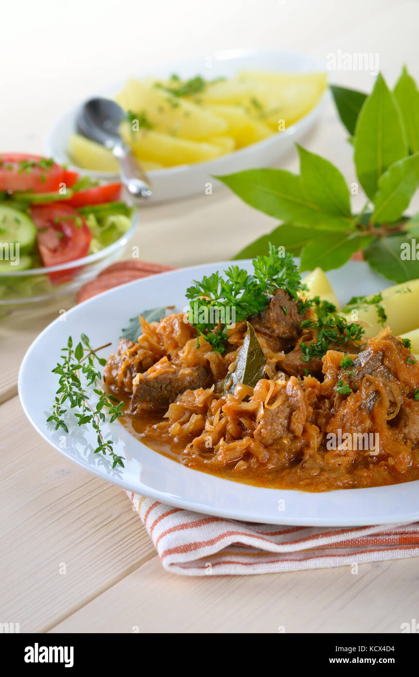 Typical Hungarian goulash (pork and beef) with pickled white cabbage (sauerkraut) and boiled potatoes Stock Photo