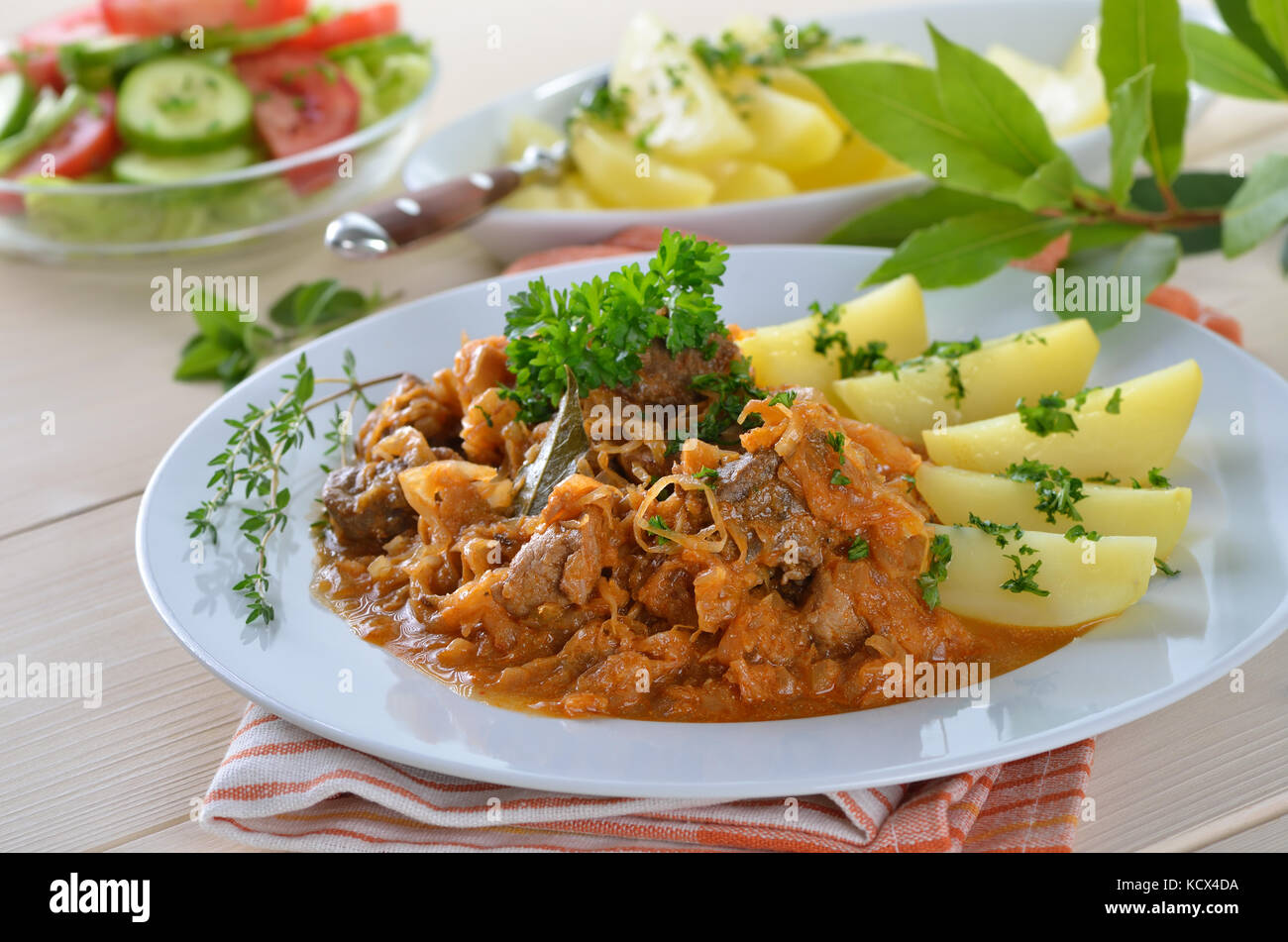 Typical Hungarian goulash (pork and beef) with pickled white cabbage (sauerkraut) and boiled potatoes Stock Photo