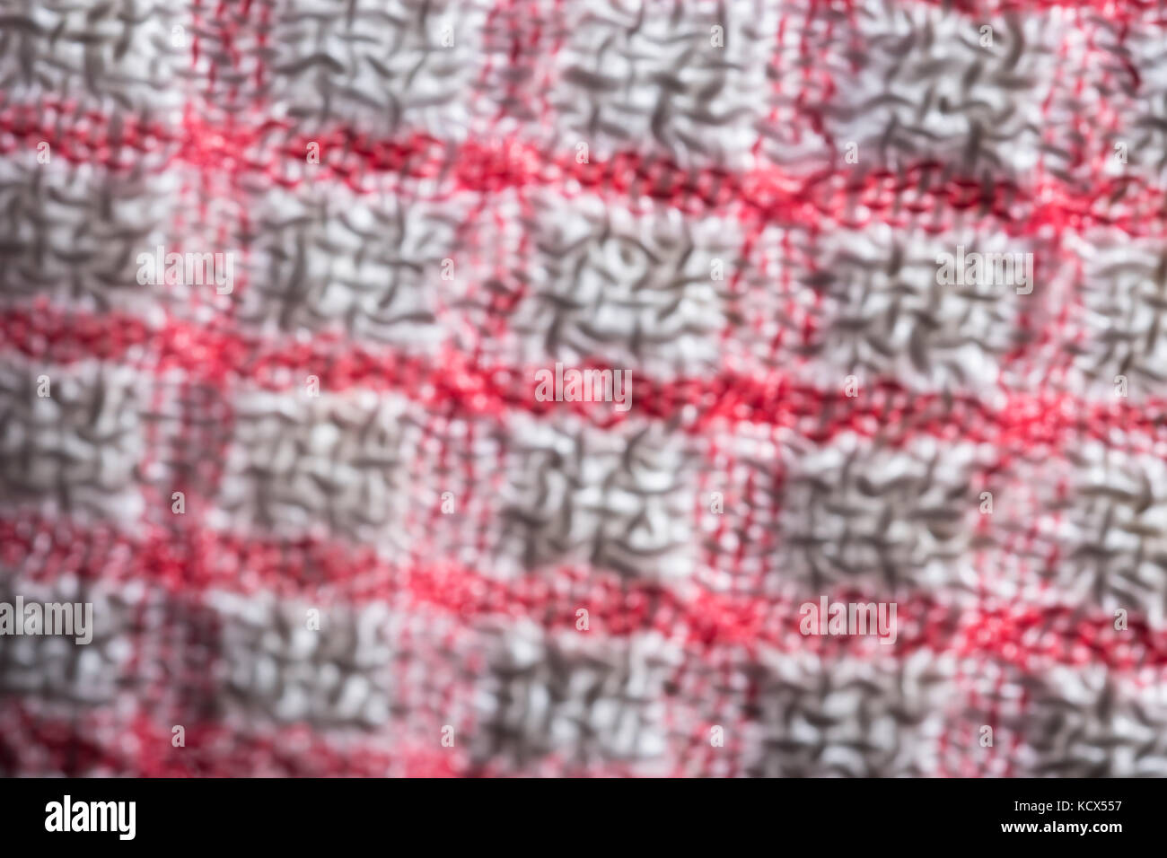 Softened, blurry, close-up macro shot of the warp and weft threads of a red and white teacloth. Stock Photo