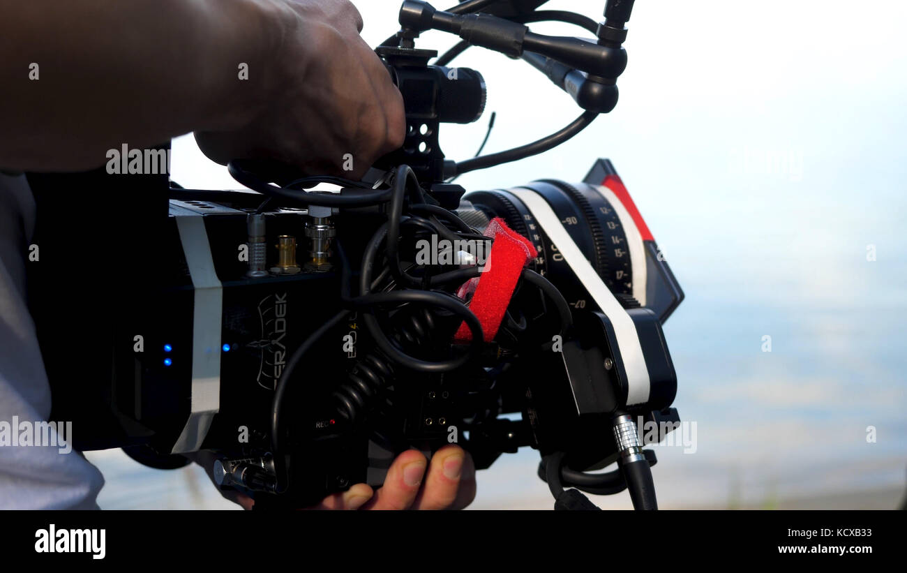 Man holding a camera filming a movie in the forest. Expensive camera