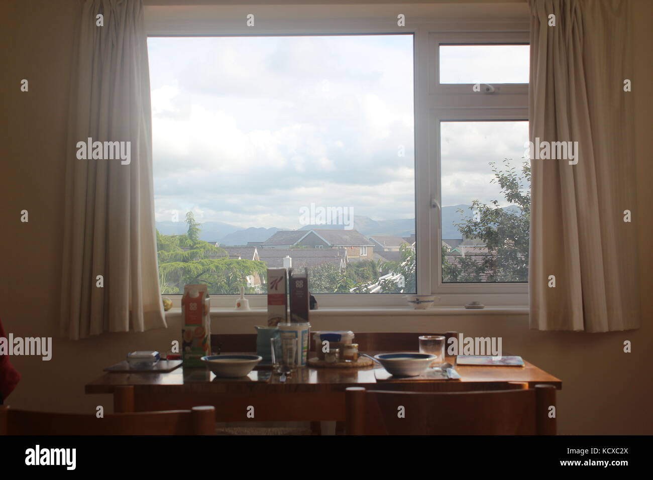 Breakfast set up on kitchen table, in front of window looking out over