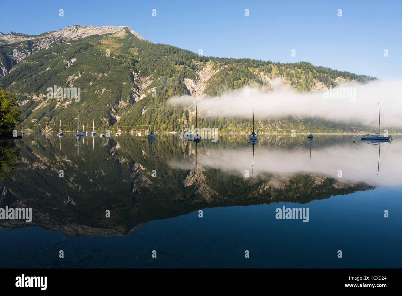 Mount Seekarspitze, sailing boats and yachts in the morning sun reflected in the calm surface of the Lake Achensee in autumn, Tyrol, Austria Stock Photo