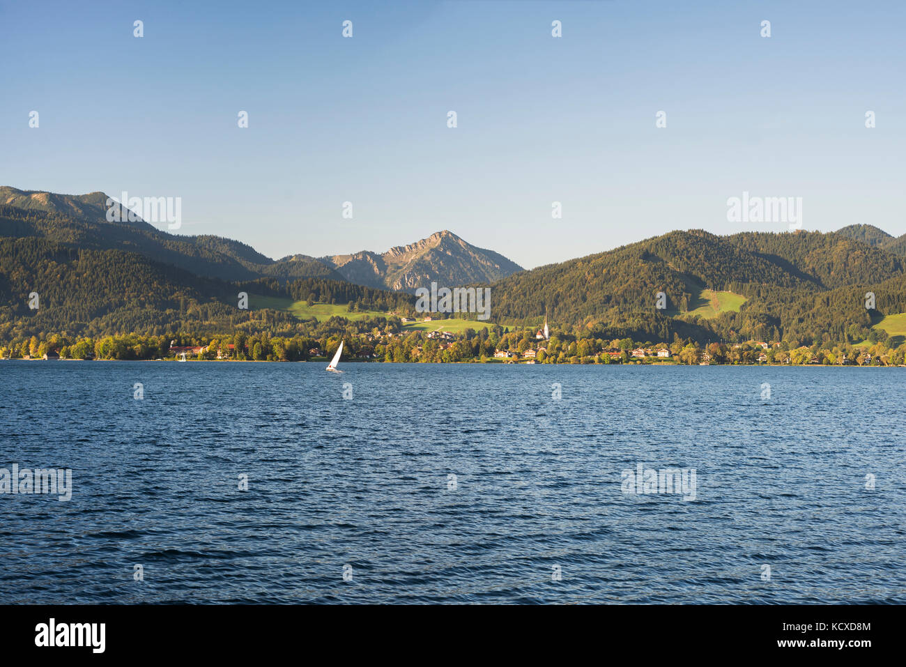 Yacht sailing on Lake Tegernsee in front of Bad Wiessee in the Bavarian Alps with autumn forests,Bavaria,Germany Stock Photo
