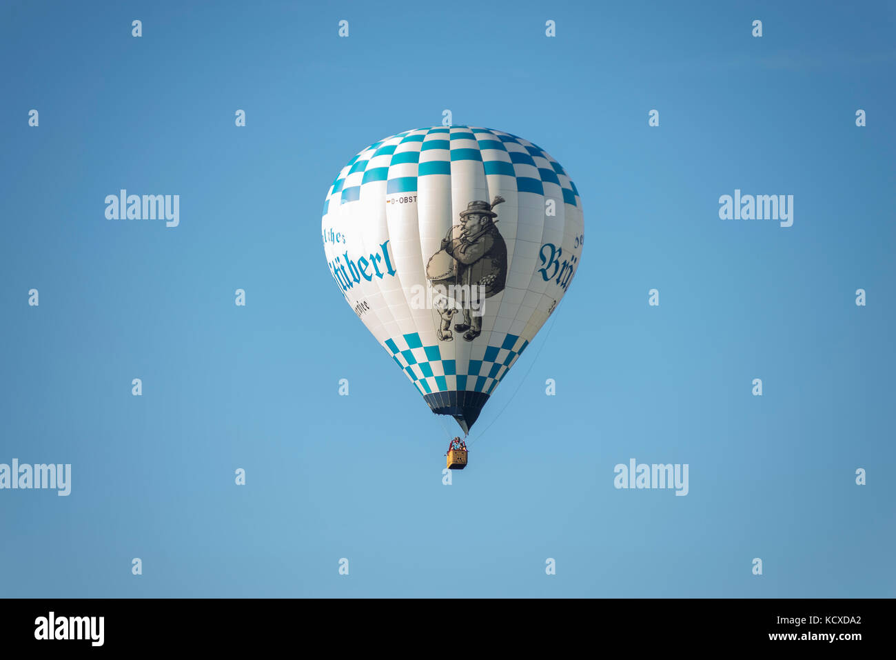 Blue and white hot-air balloon drivers with lettering Bräustüberl and drawing of a man and a dog in the sky in the morning sun, Bavaria, Germany Stock Photo