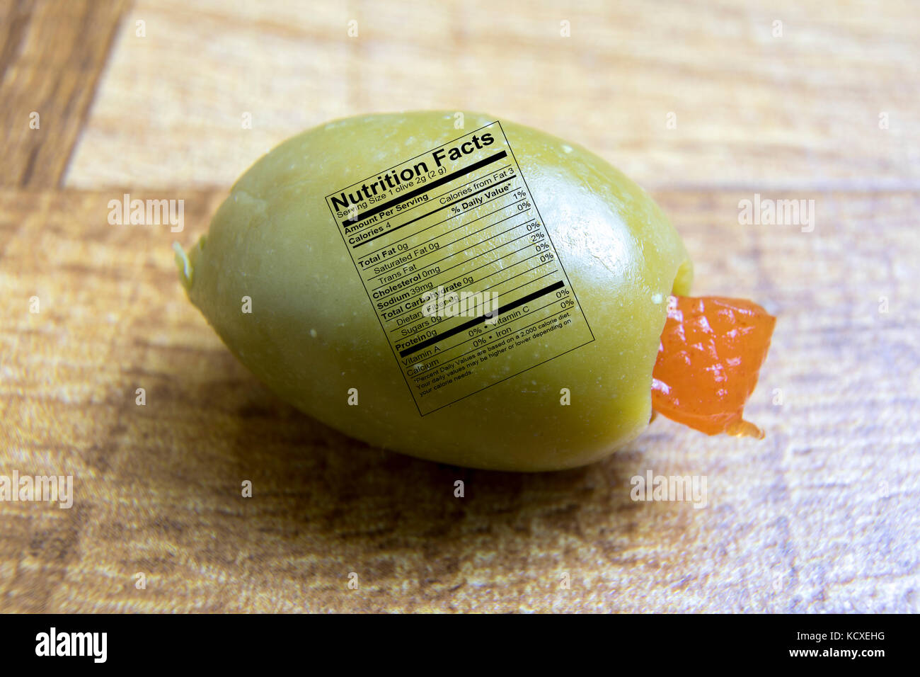 Close up of green olive with pimento and nutrition label on wooden